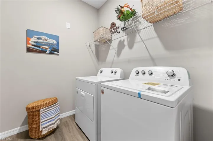 Laundry room with light wood-type flooring and washing machine and clothes dryer