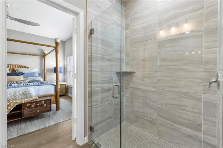 Bathroom featuring connected bathroom, a stall shower, wood finished floors, and ceiling fan