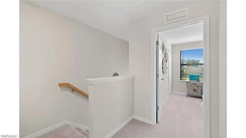 Hallway with light carpet and an upstairs landing