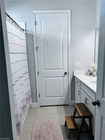 Full bath with vanity, curtained shower, and light tile patterned flooring