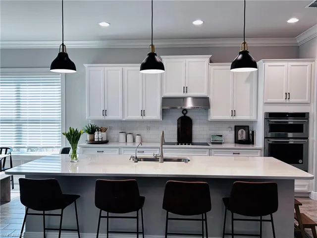 Kitchen featuring crown molding, dark wood-style flooring, white cabinets, pendant lighting, and tasteful backsplash