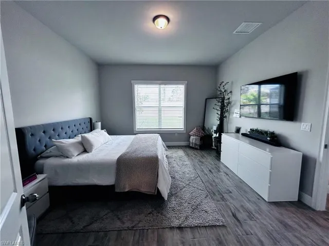 Bedroom with dark wood finished floors and baseboards