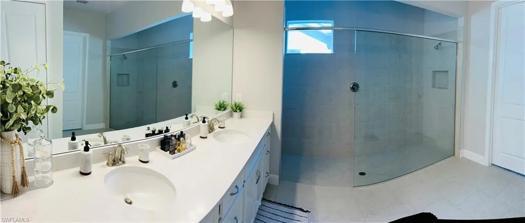 Full bath featuring double vanity, a stall shower, and light tile patterned floors