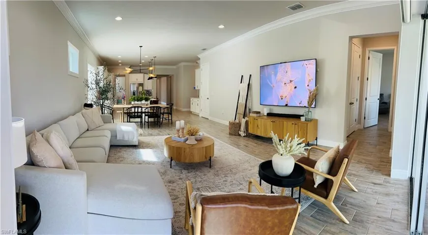 Living room with ornamental molding, wood tiled floors, and recessed lighting