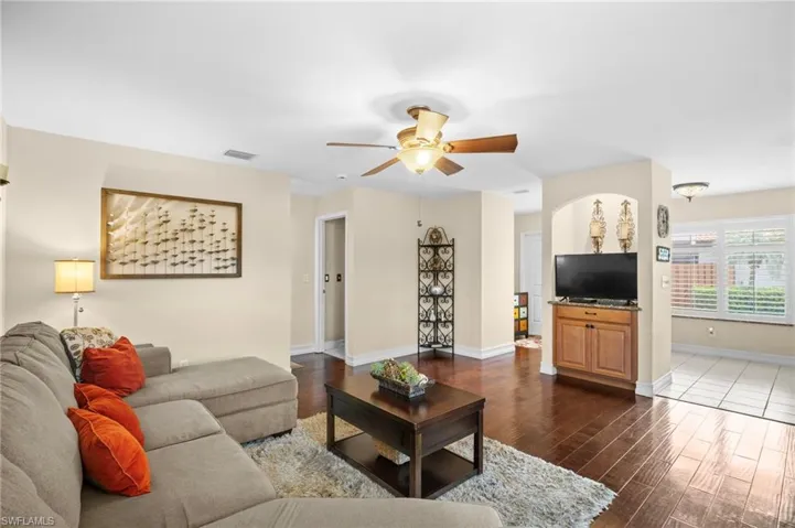 Living area featuring dark wood-style floors and ceiling fan