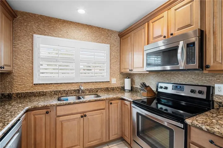 Kitchen with appliances with stainless steel finishes, dark stone countertops, and decorative backsplash