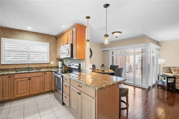 Kitchen with stainless steel appliances, a breakfast bar, a peninsula, tasteful backsplash, and dark stone countertops