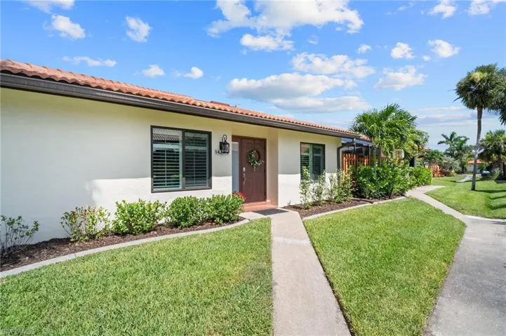 View of front of property with a front lawn, stucco siding, and a tiled roof
