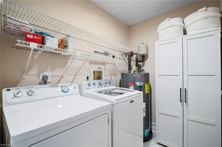 Laundry area featuring washer and dryer, electric water heater, and cabinet space