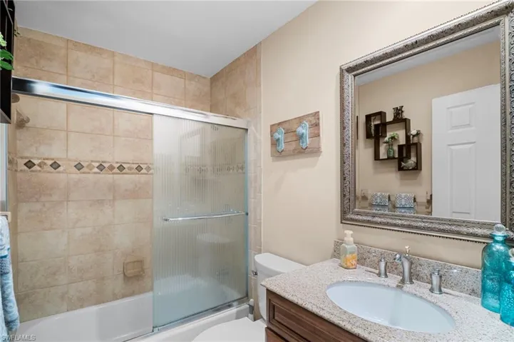 Bathroom featuring vanity and bath / shower combo with glass door