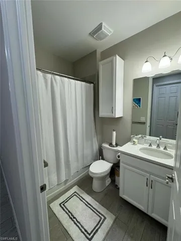 Full bathroom with wood-type flooring, vanity, shower / tub combo, and toilet