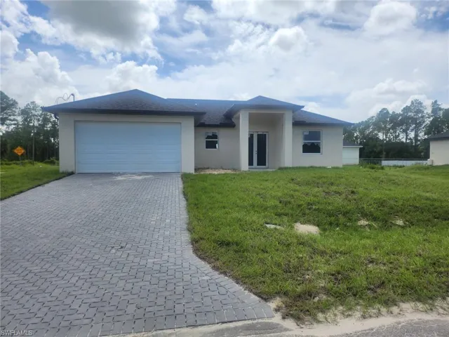 Single story home with stucco siding, decorative driveway, an attached garage, and a front yard