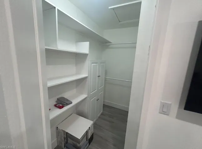 Walk in closet featuring dark wood-style flooring and attic access