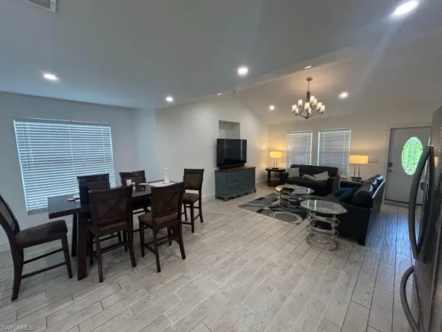 Dining room with hanging lights, light wood-style flooring, and lofted ceiling