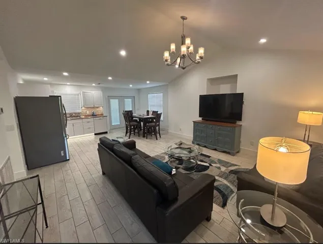 Living area featuring wood finish floors, vaulted ceiling, and hanging lights