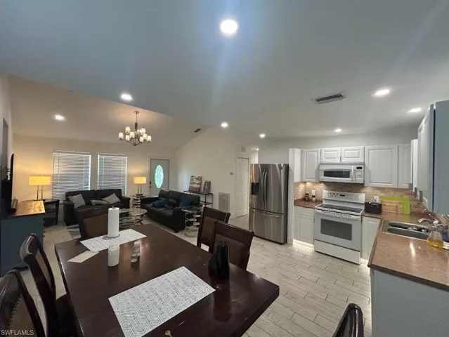 Dining area with vaulted ceiling, hanging lights, and wood finish floors