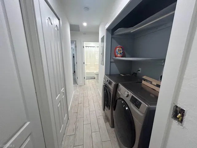 Laundry area with light wood-type flooring, washer and dryer, and recessed lighting