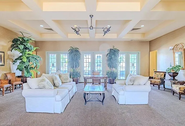 Living room with coffered ceiling, beam ceiling, plenty of natural light, and carpet