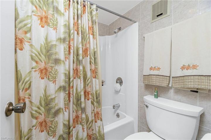 Tub shower in hall bath with tiled walls.