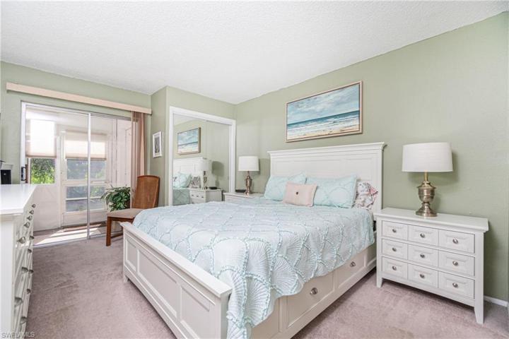 Lovely ensuite primary bedroom has sliders to rear Florida Room.