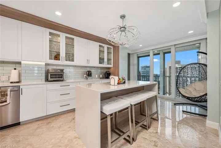 Kitchen with marble finish floor, light countertops, stainless steel dishwasher, decorative backsplash, and white cabinetry
