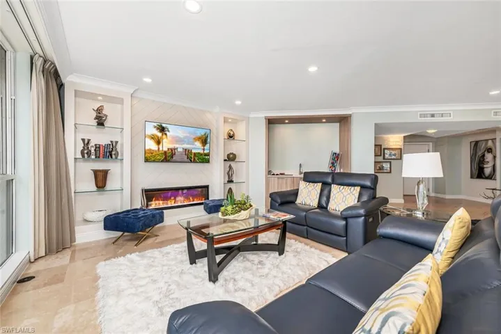 Living room featuring a glass covered fireplace, built in features, recessed lighting, and ornamental molding