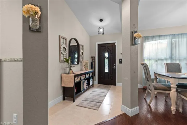 Inviting entryway featuring a dark wood front door with decorative glass inserts, a contemporary light fixture, and tile flooring