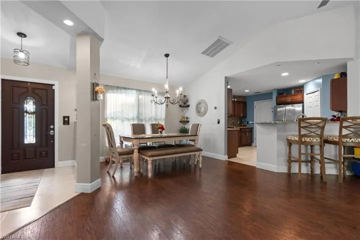 Spacious interior featuring wood flooring, a dining area with a chandelier, and a kitchen with a breakfast bar