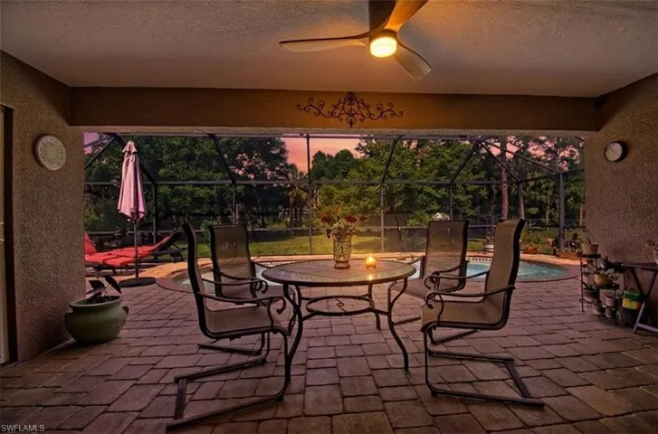 The property features a screened-in patio area with brick pavers and a ceiling fan, offering a view of the pool and surrounding trees