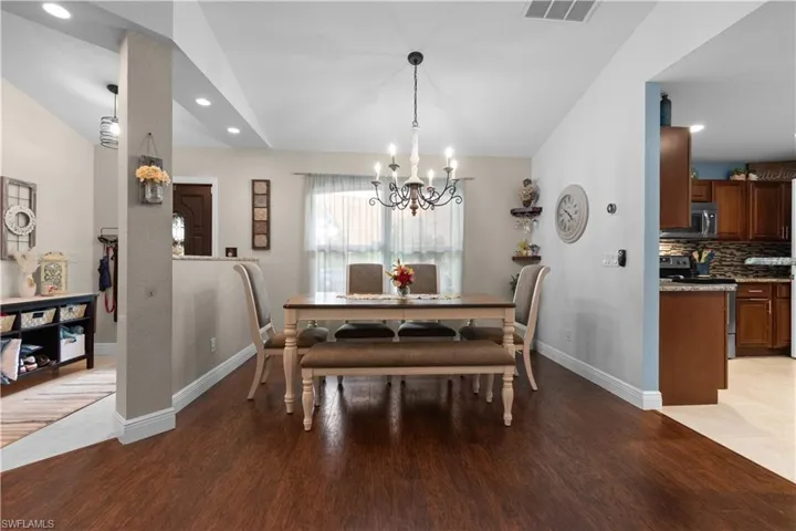 The property features rich wood flooring, recessed lighting, and a kitchen with wooden cabinetry, stainless steel appliances, and a tiled backsplash