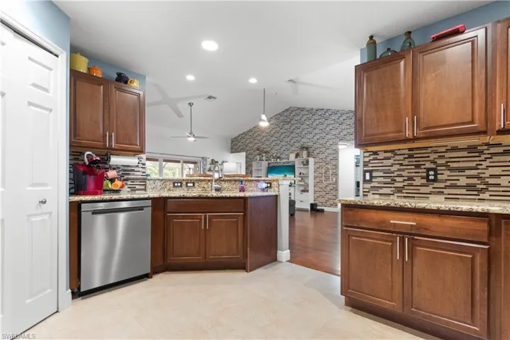 The kitchen features wooden cabinetry, granite countertops, a tiled backsplash, and stainless steel appliances