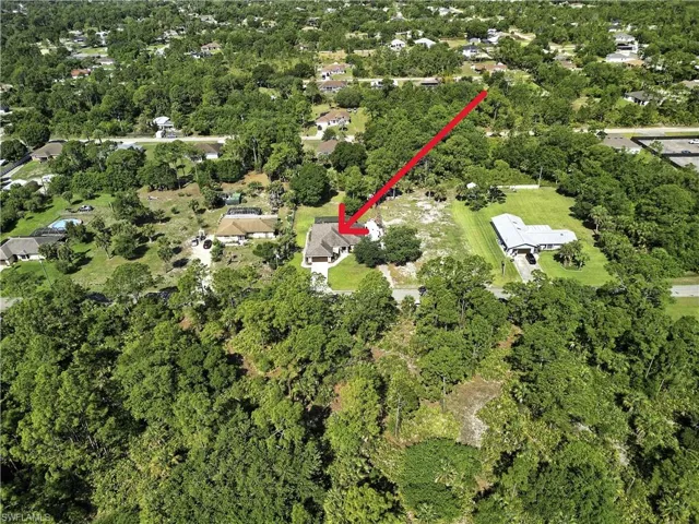 Aerial view showcasing the property's expansive lot with mature trees and a well-maintained lawn