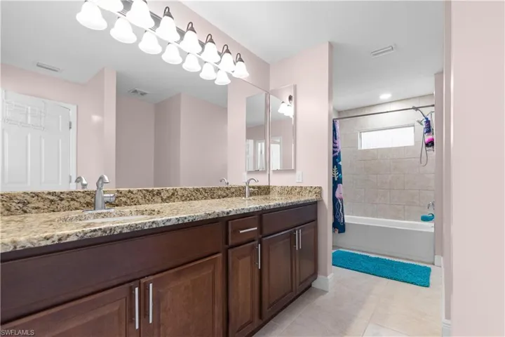 Guest bathroom features dual sinks and a shower/tub combo