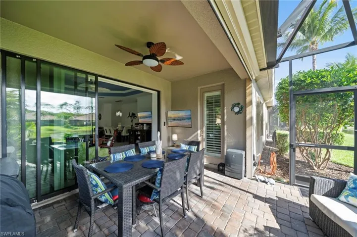 The screened-in patio features a ceiling fan, sliding glass doors, and paver flooring