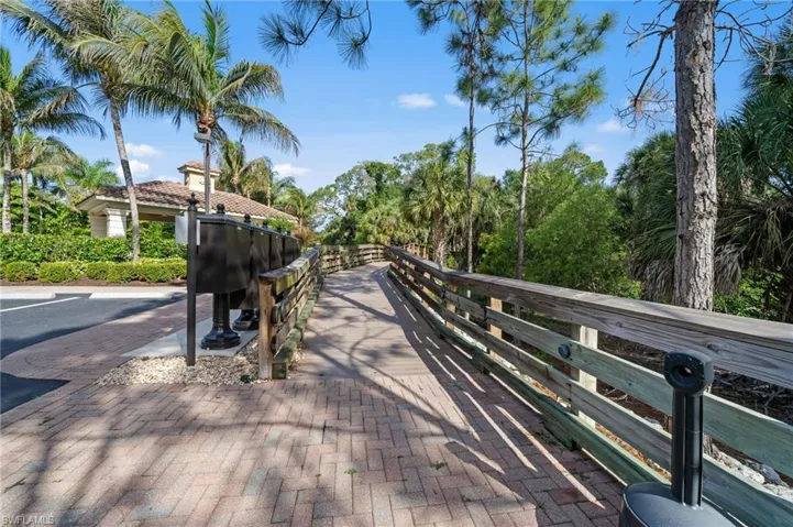 This community offers access to a brick paver pathway and a wooden boardwalk, surrounded by lush vegetation and palm trees