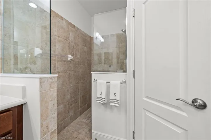 The bathroom features a tiled shower with a glass enclosure