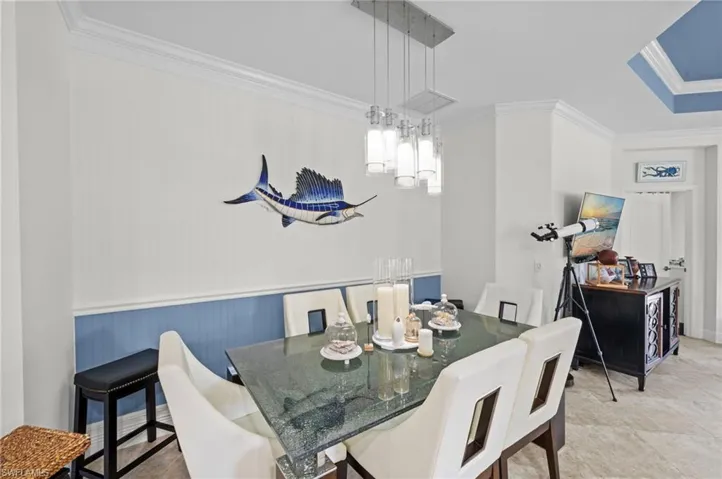 The dining area features crown molding, a modern chandelier, and a decorative tray ceiling