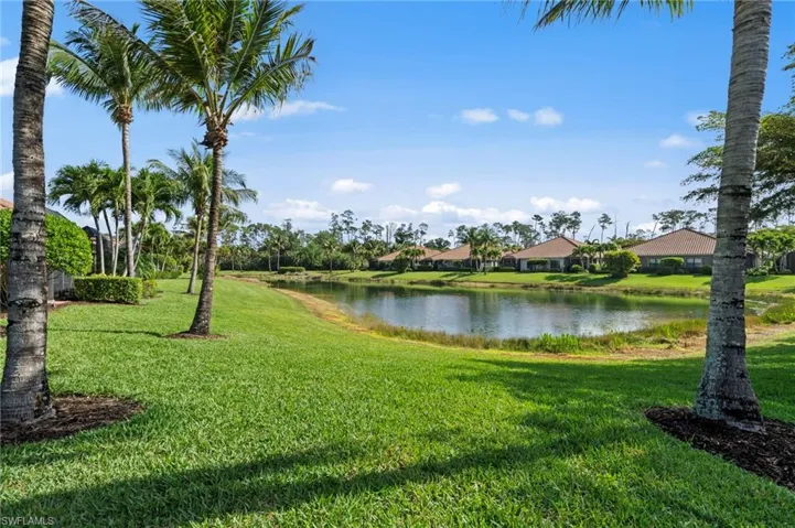 The property features a serene lake view and a landscaped lawn with palm trees