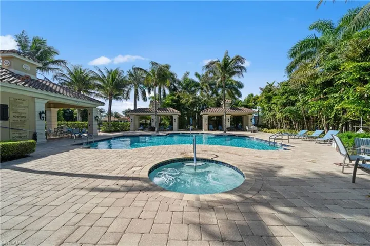 The property features a large outdoor pool and a separate hot tub, surrounded by extensive paver decking