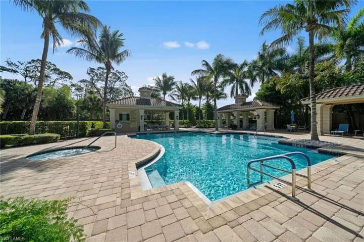 This property features an inviting swimming pool with a separate spa, surrounded by a paved patio area