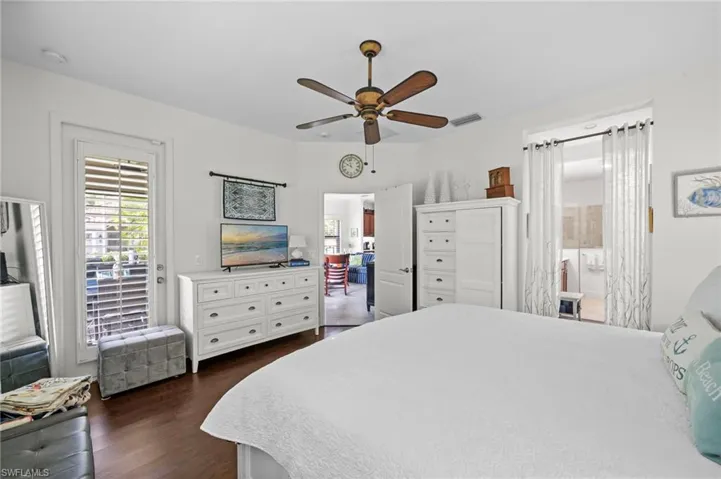 This room features hardwood floors, a ceiling fan, and white walls