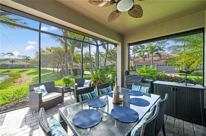 The screened patio features a ceiling fan, tiled flooring, and views of a pond and lush landscaping