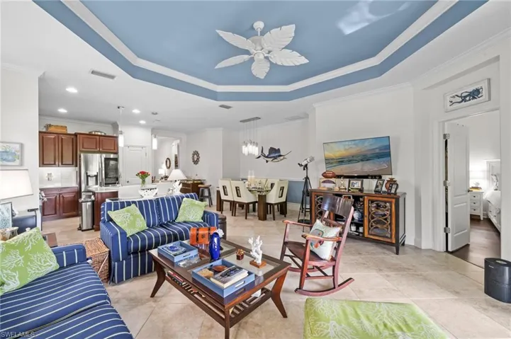 The living room features a tray ceiling with a blue accent, recessed lighting, and tile flooring