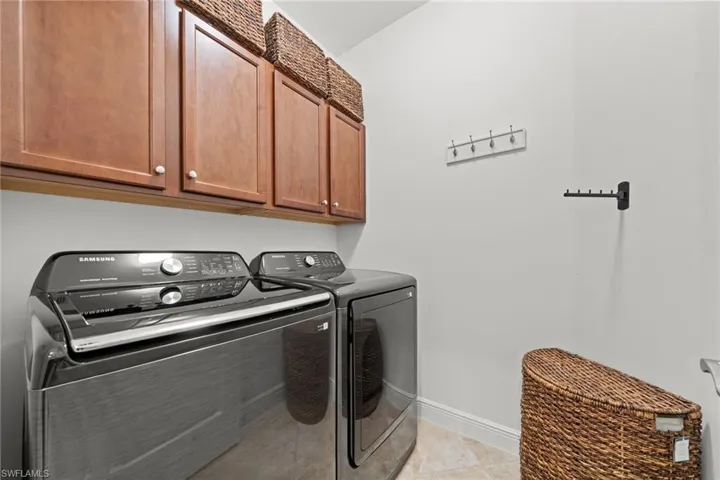 Laundry area featuring upper cabinetry with light wood finishes and ample wall space