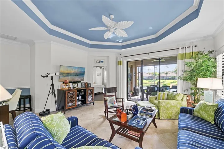 The living area features a tray ceiling with a blue accent, tile flooring, and large sliding glass doors providing outdoor access