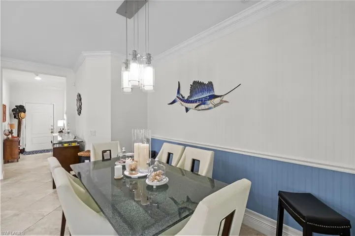 Dining area featuring a modern chandelier, wainscoting, and tile flooring
