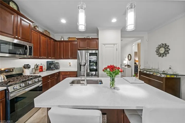 The kitchen features stainless steel appliances, rich wood cabinetry, and a spacious island with a sink and light-colored countertop