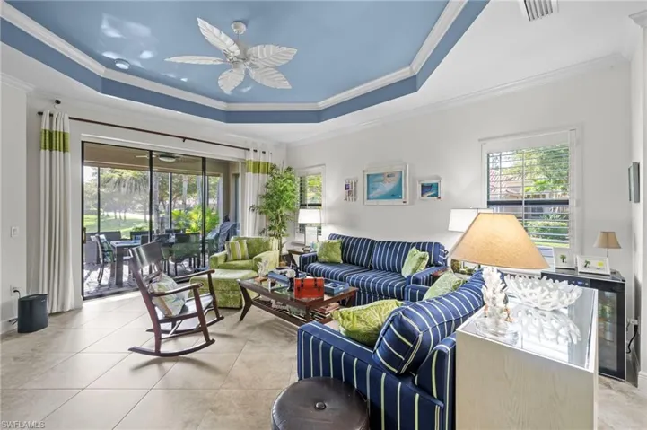 Living area featuring a tray ceiling with a ceiling fan, tiled flooring, and large sliding glass doors leading to an outdoor screened patio