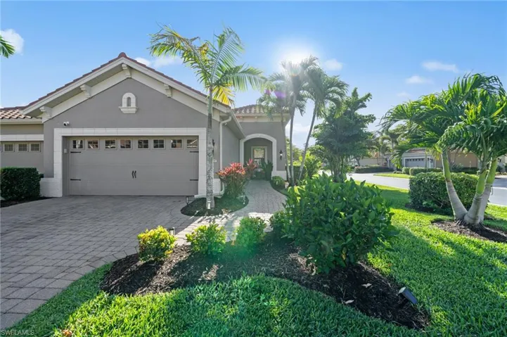 The property features a paver driveway and walkway, a two-car garage, and a stucco exterior with a tiled roof
