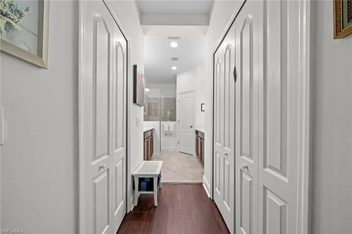 Hallway featuring white bi-fold doors, recessed lighting, and rich brown flooring